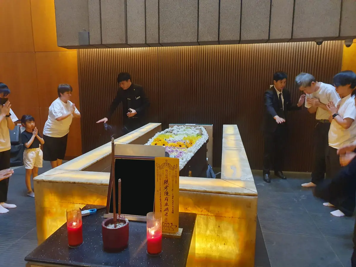 Family gathering around the casket for final Buddhist prayers