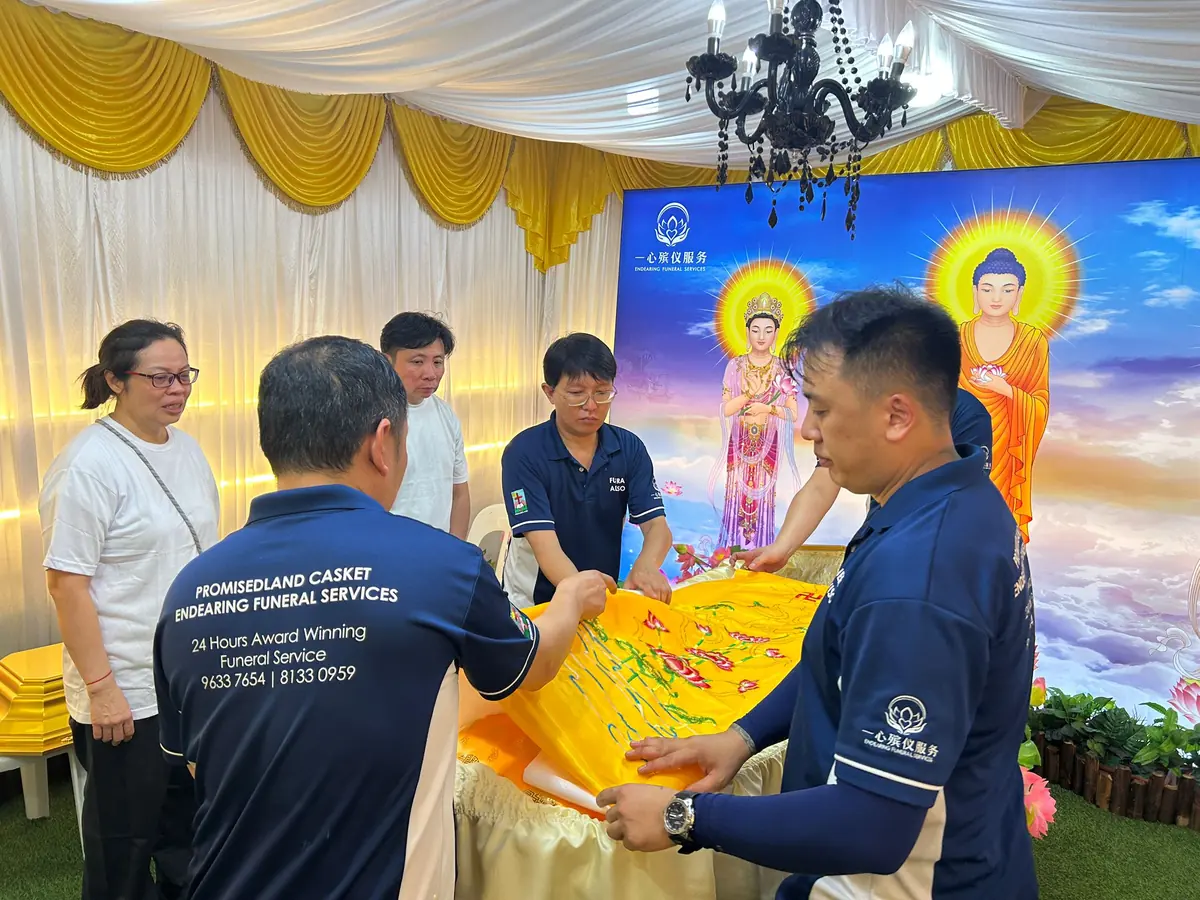 Family placing a Buddhist blessing cloth during final rites